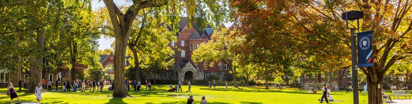 Students walk across Macalester's Great Lawn, surrounded by autumnal colors.