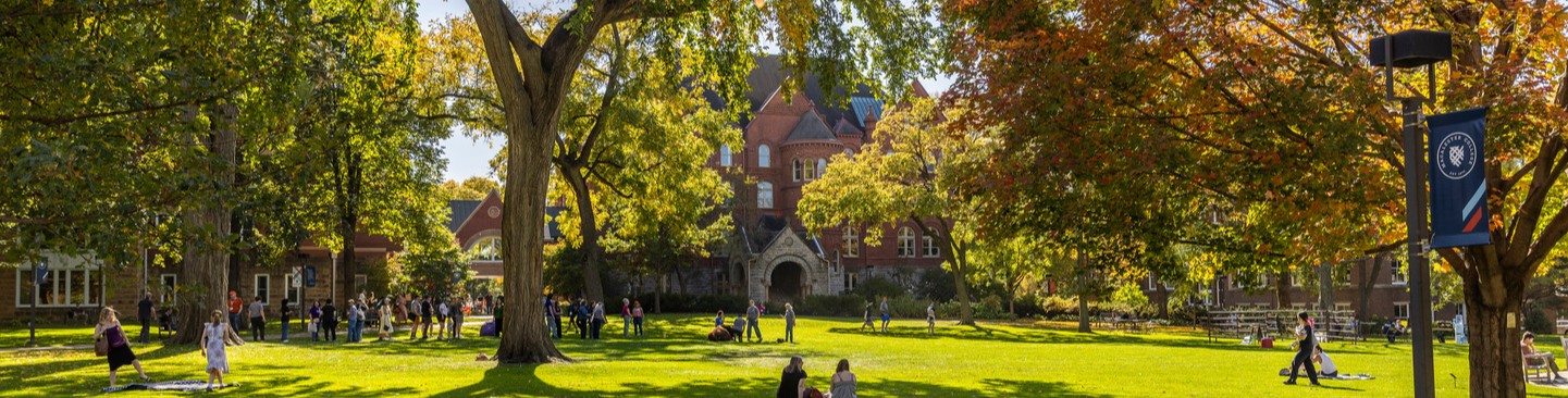Students walk across Macalester's Great Lawn, surrounded by autumnal colors.