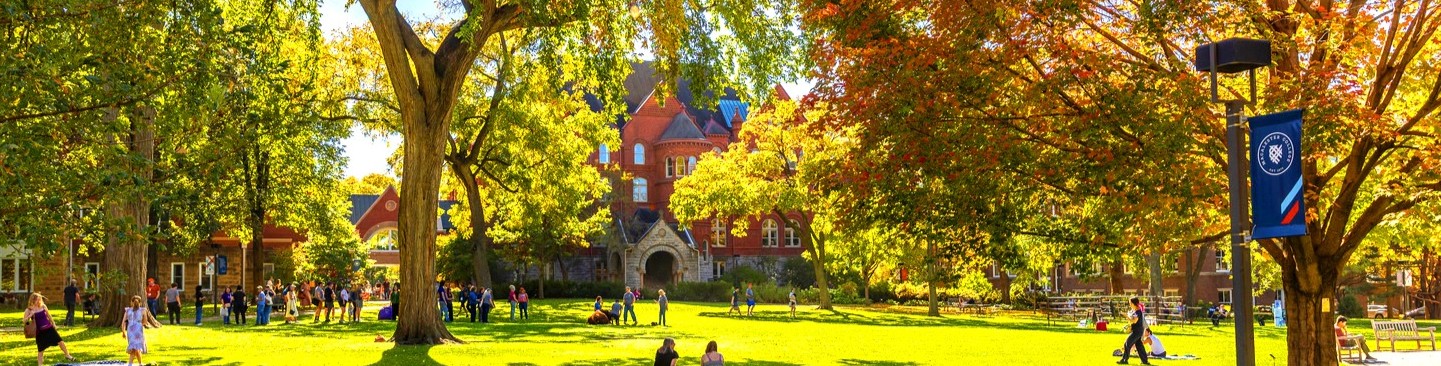 Students walk across Macalester's Great Lawn, surrounded by autumnal colors.